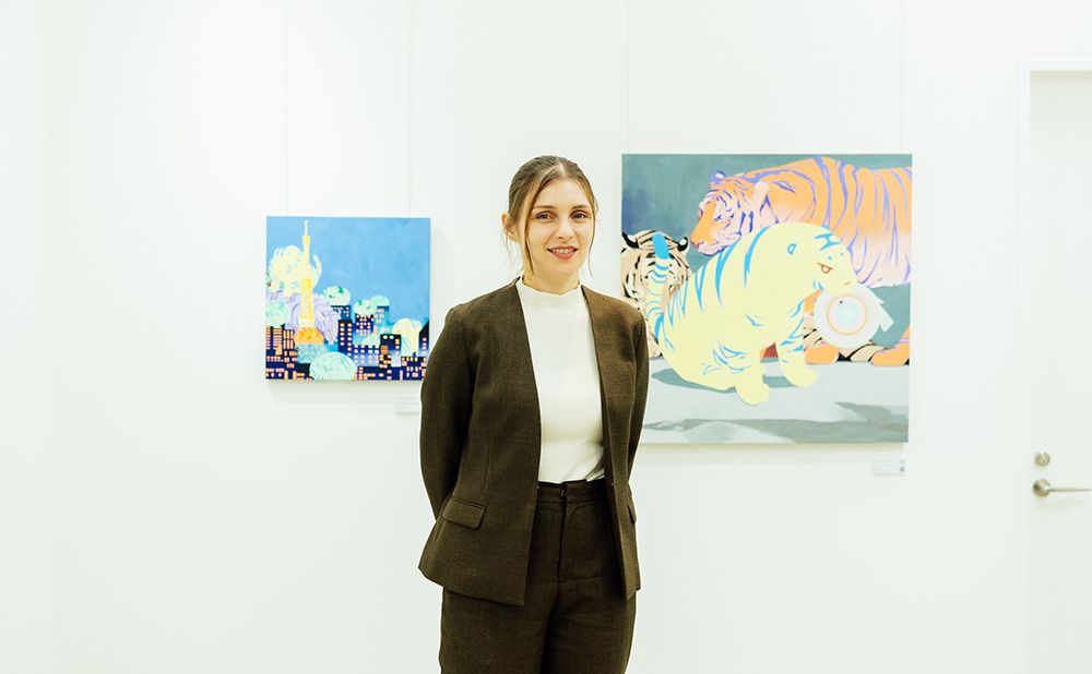 Adeline standing in front of her work in the gallery