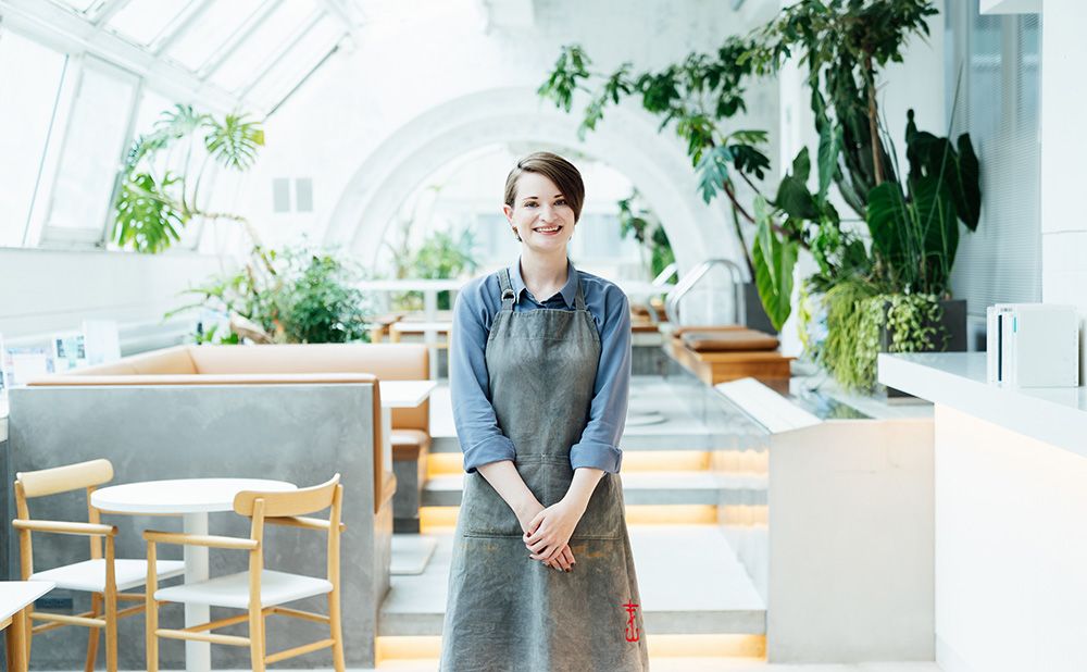 Rachel Nicholson stands in front of the hotel restaurant, smiling in her apron.