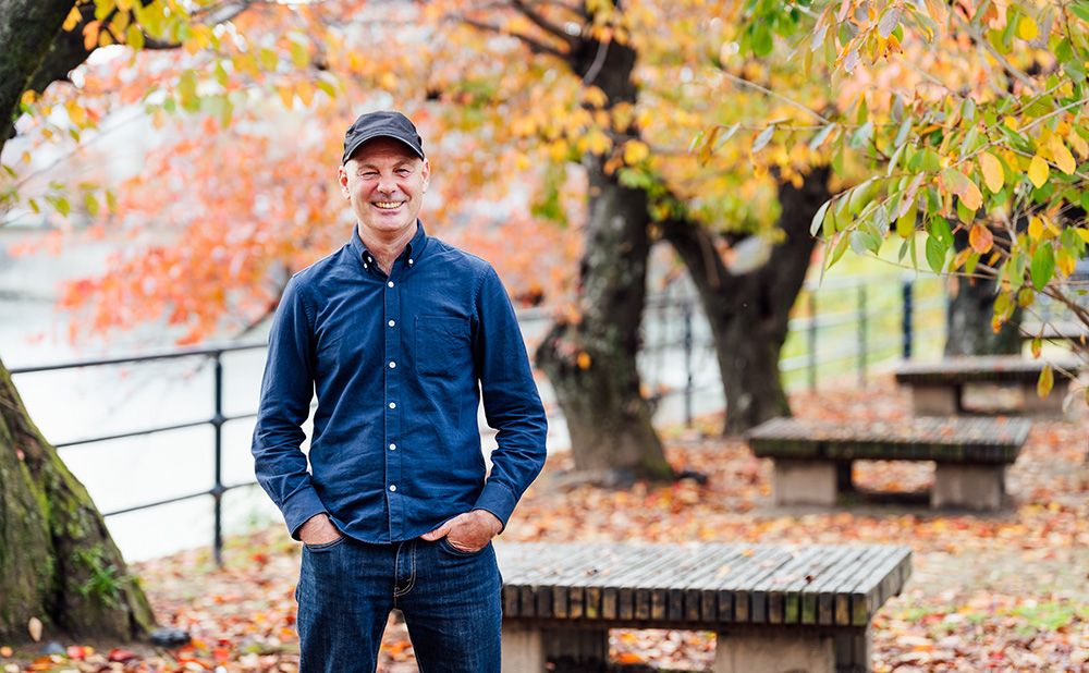 Paul Walsh smiles against the backdrop of the street trees in fall foliage.